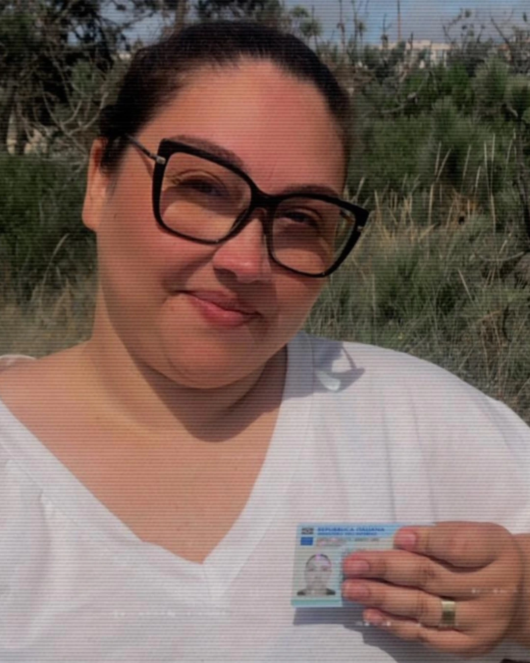 Cliente da Speranza sorrindo ao ar livre, segurando o documento de identidade italiano