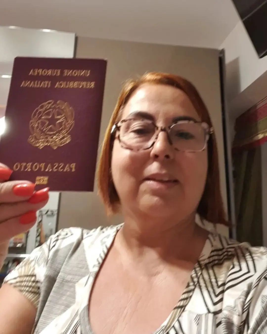 Cliente da Speranza segurando o passaporte italiano recém-emitido