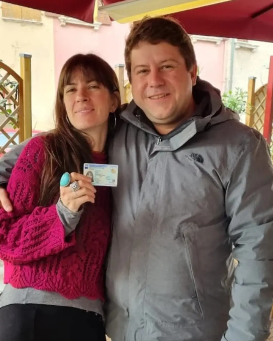 Casal de clientes da Speranza posando ao ar livre, com o documento de identidade italiano