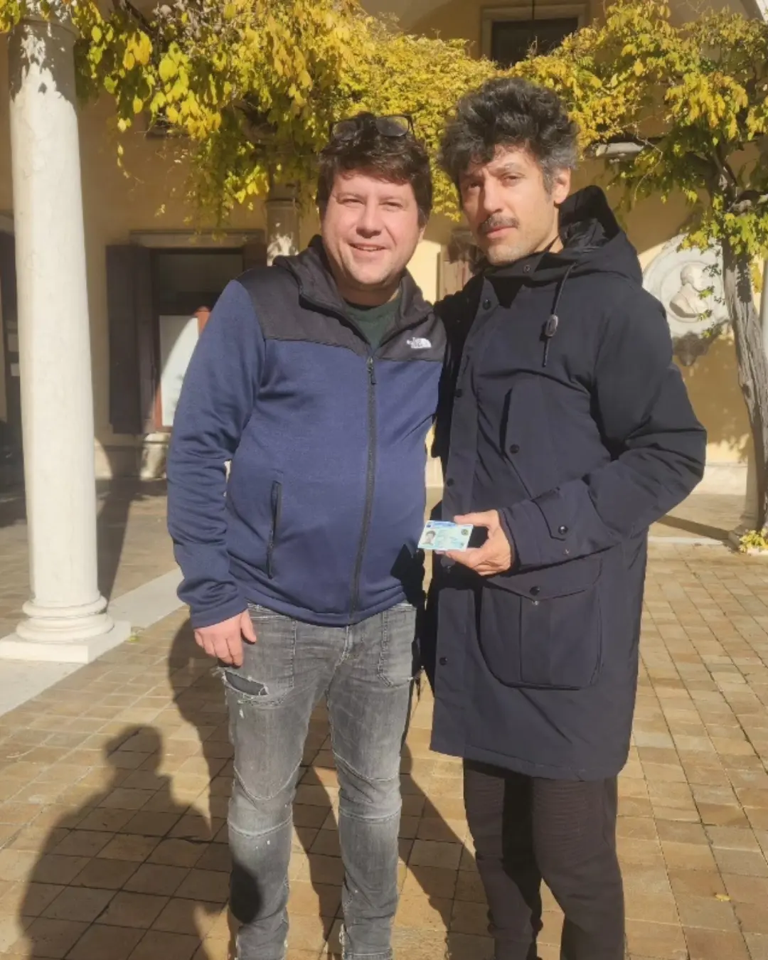Dois clientes da Speranza posando juntos, um segurando o documento de identidade italiano