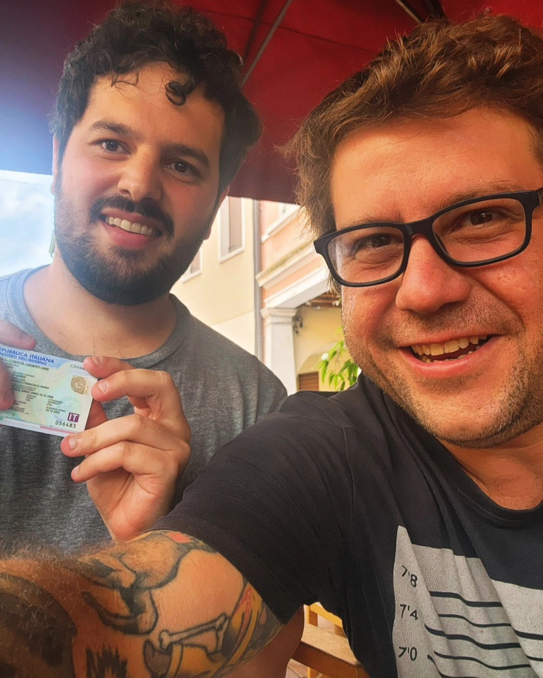 Dois clientes da Speranza sorrindo juntos, um segurando o documento de identidade italiano